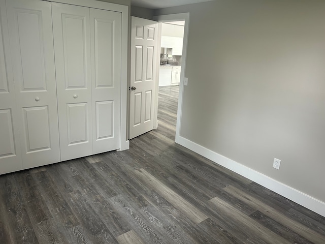 unfurnished bedroom with sink, a closet, and dark wood-type flooring