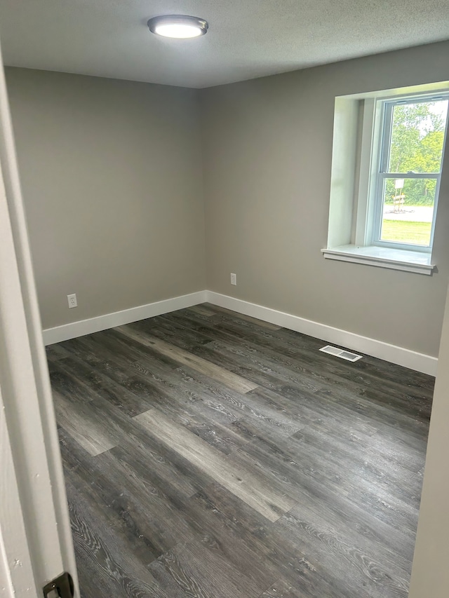 empty room featuring dark wood-type flooring and a textured ceiling