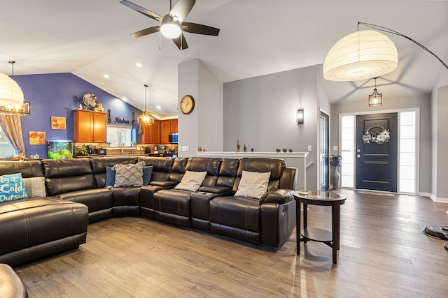 living room featuring vaulted ceiling, light hardwood / wood-style floors, and ceiling fan with notable chandelier