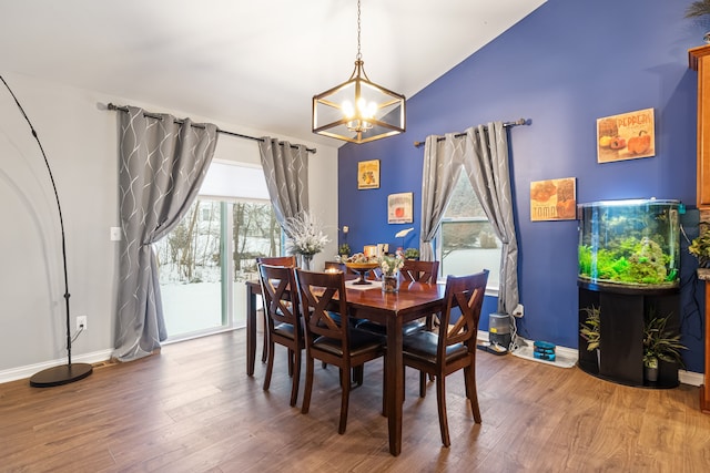 dining space featuring an inviting chandelier, a wealth of natural light, lofted ceiling, and hardwood / wood-style flooring