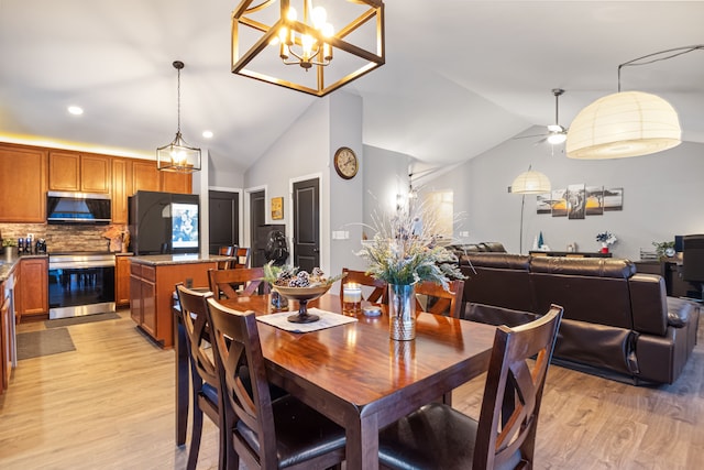 dining area with light hardwood / wood-style flooring, vaulted ceiling, and ceiling fan with notable chandelier