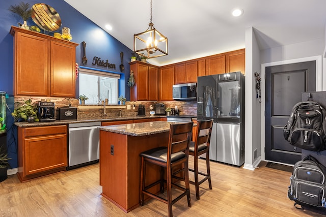 kitchen with stainless steel appliances, a center island, dark stone countertops, tasteful backsplash, and light wood-type flooring