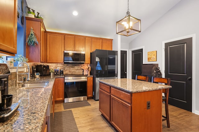 kitchen featuring stainless steel appliances, sink, backsplash, hanging light fixtures, and a kitchen island