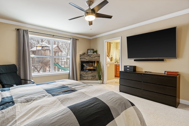 bedroom with connected bathroom, light colored carpet, ceiling fan, ornamental molding, and a stone fireplace