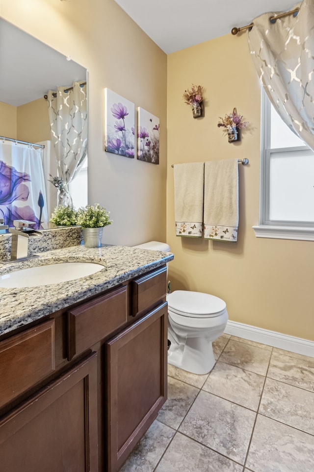 bathroom with tile patterned floors, a wealth of natural light, vanity, and toilet