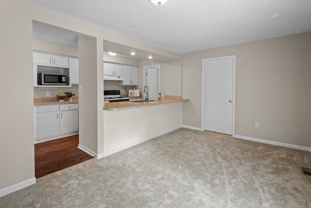 kitchen featuring sink, carpet flooring, white gas stove, a textured ceiling, and white cabinets