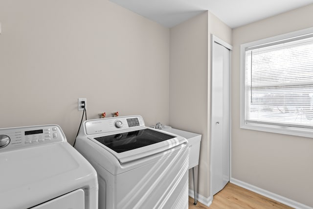 laundry area featuring washing machine and dryer and light hardwood / wood-style flooring