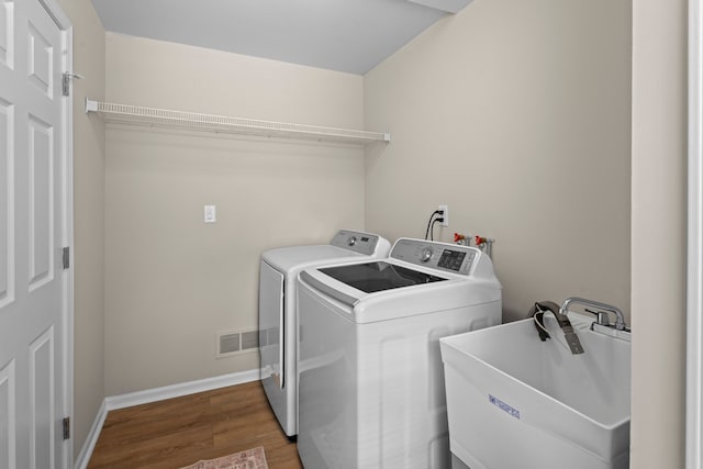 clothes washing area featuring washer and clothes dryer, dark hardwood / wood-style floors, and sink