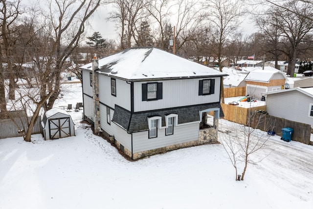 snow covered back of property with a storage shed