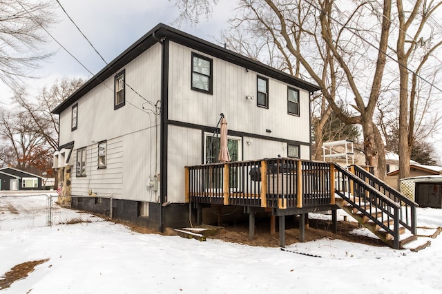 snow covered rear of property with a deck