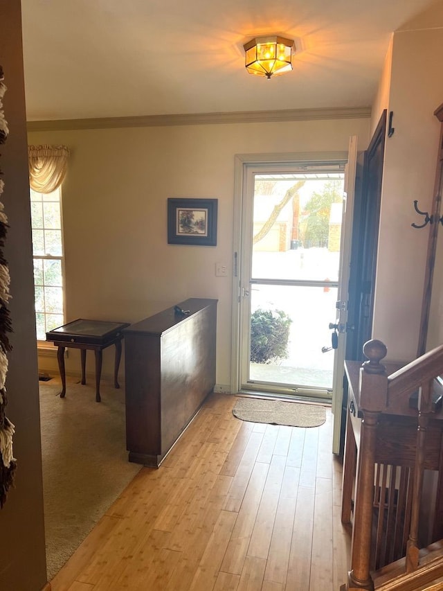 doorway with ornamental molding and light hardwood / wood-style flooring