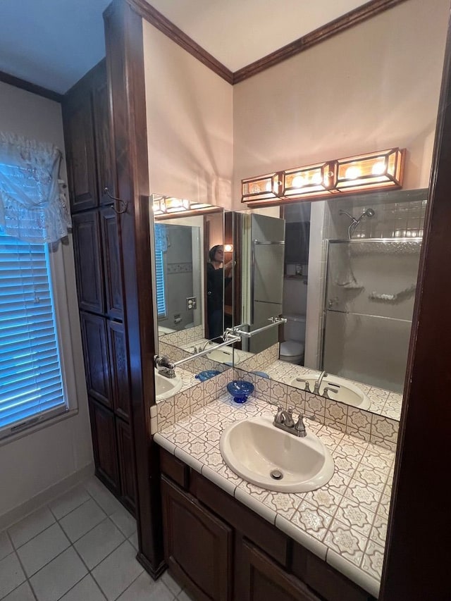 bathroom featuring toilet, tile patterned flooring, crown molding, an enclosed shower, and vanity