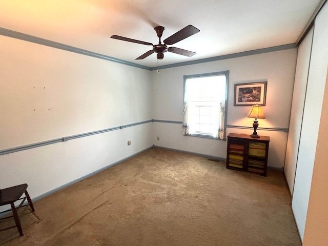 empty room with ceiling fan, ornamental molding, and carpet