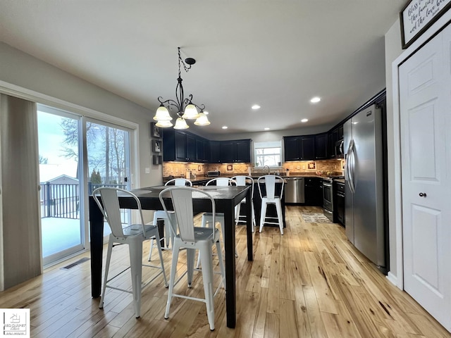 dining room with light hardwood / wood-style floors, an inviting chandelier, and sink