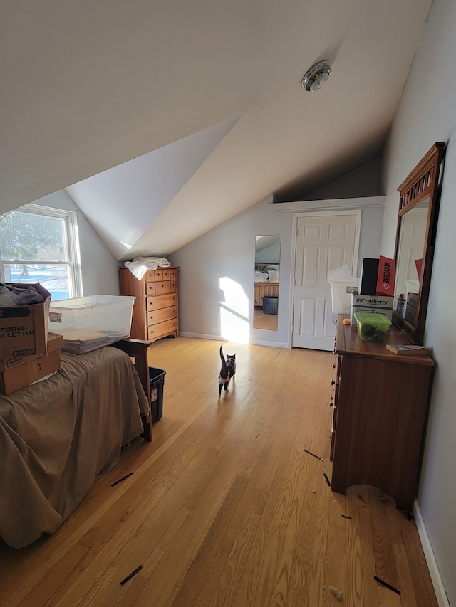 bedroom with light wood-type flooring and vaulted ceiling