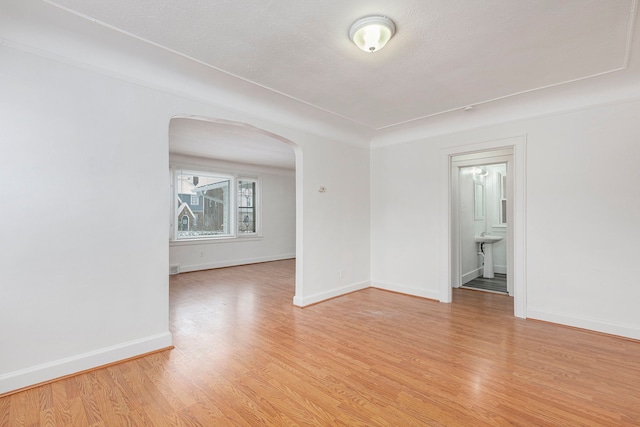 spare room featuring light hardwood / wood-style floors and a textured ceiling