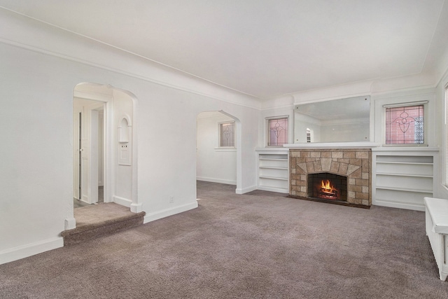 unfurnished living room featuring carpet, a fireplace, and crown molding