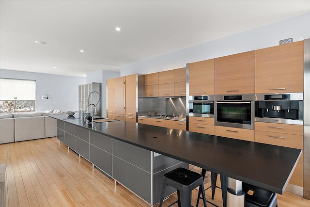 kitchen featuring a spacious island, a kitchen bar, oven, and sink