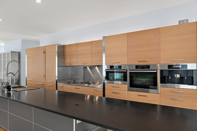 kitchen featuring tasteful backsplash, sink, and stainless steel oven