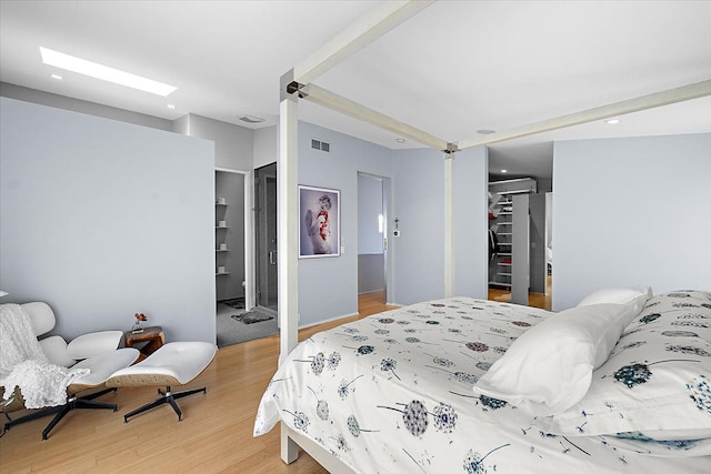 bedroom featuring a spacious closet, wood-type flooring, a closet, and ensuite bathroom