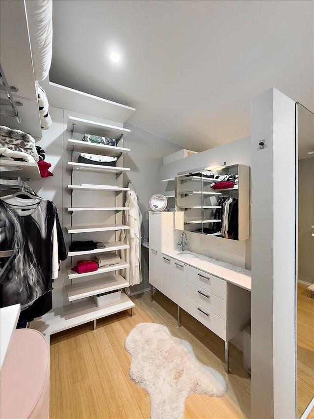 walk in closet with light hardwood / wood-style floors