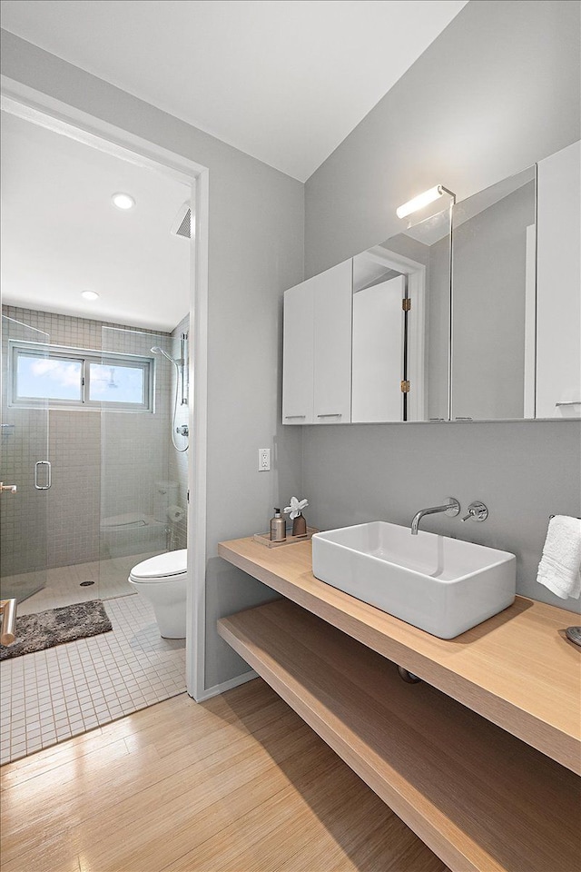 bathroom with wood-type flooring, toilet, a shower with shower door, and vanity