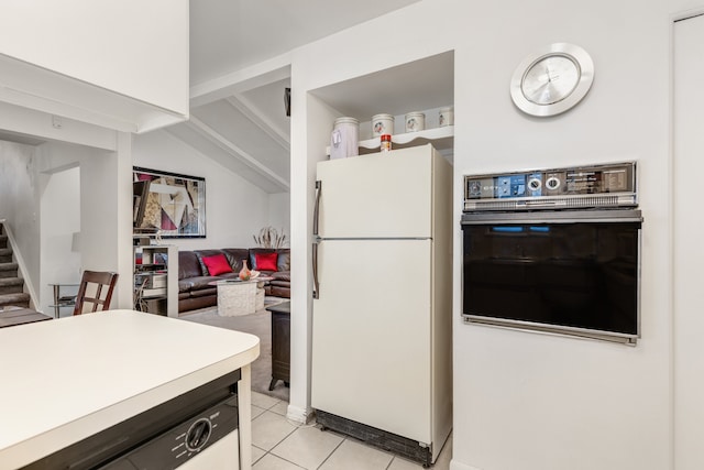 kitchen with black oven, vaulted ceiling, white fridge, and light tile patterned floors