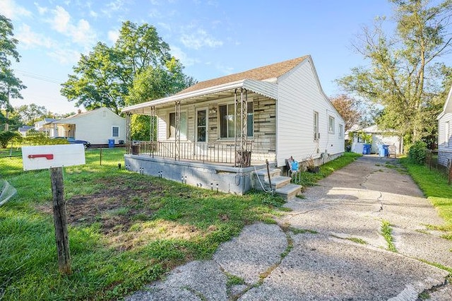 bungalow-style home featuring covered porch and a front yard