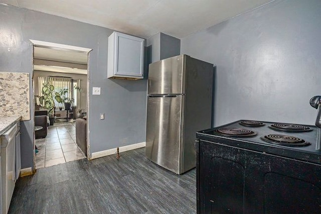 kitchen featuring stainless steel refrigerator, light stone countertops, dark wood-type flooring, black range with electric cooktop, and white cabinets