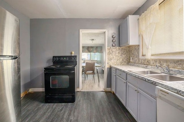 kitchen featuring stainless steel refrigerator, sink, black electric range, white dishwasher, and white cabinets