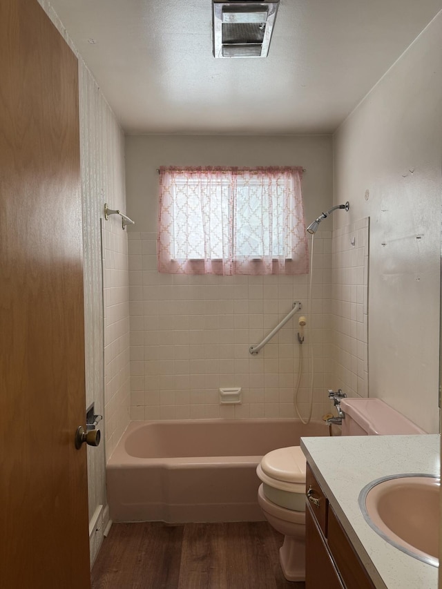 full bathroom featuring toilet, vanity, hardwood / wood-style flooring, and tiled shower / bath combo