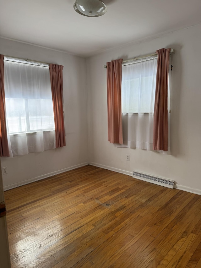 empty room with a wealth of natural light and hardwood / wood-style flooring