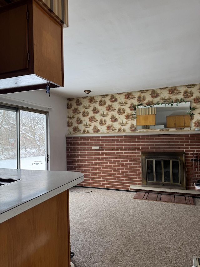 kitchen featuring light colored carpet and a brick fireplace