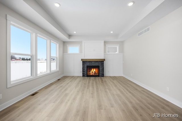 unfurnished living room featuring a tray ceiling and light hardwood / wood-style flooring