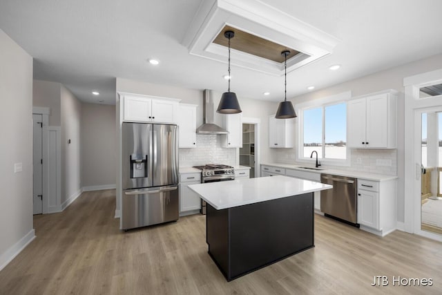 kitchen featuring stainless steel appliances, white cabinets, wall chimney range hood, a kitchen island, and sink