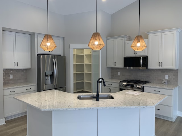 kitchen with an island with sink, decorative light fixtures, sink, appliances with stainless steel finishes, and white cabinets