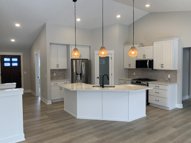 kitchen with stainless steel appliances, pendant lighting, sink, white cabinetry, and a kitchen island with sink