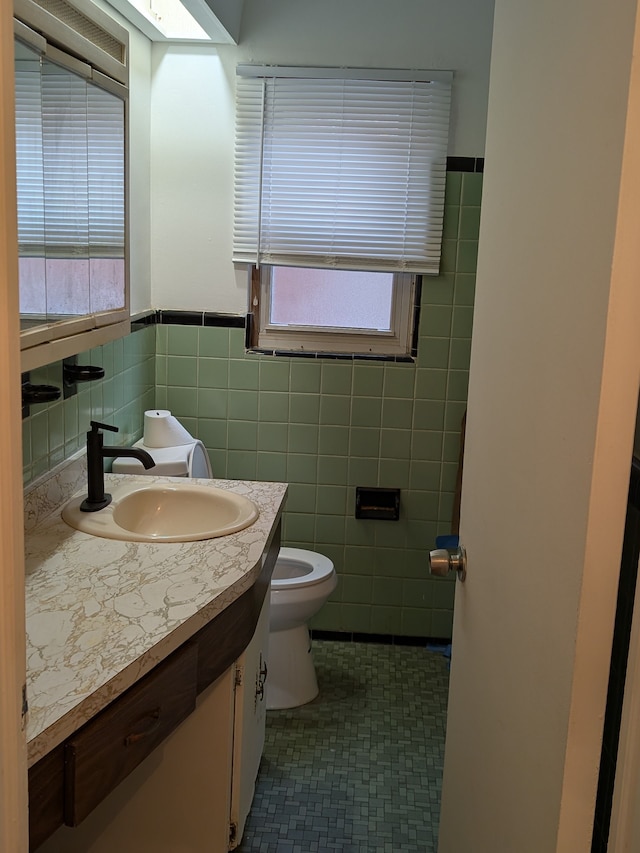 bathroom with tile walls, toilet, vanity, and tile patterned flooring