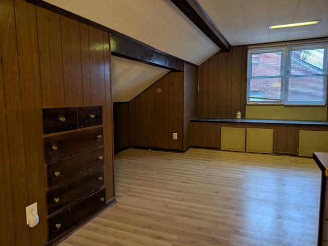 bonus room with light hardwood / wood-style flooring, wood walls, and lofted ceiling with beams