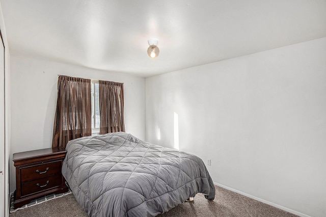 bedroom featuring dark colored carpet and baseboards