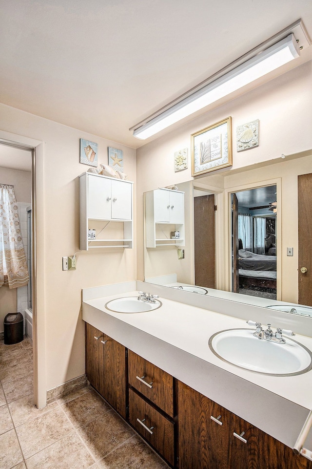 full bath with double vanity, a sink, baseboards, and ensuite bath