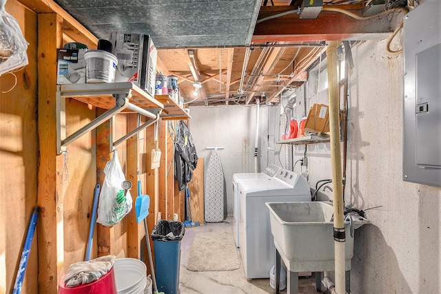 unfinished below grade area with washing machine and clothes dryer, a sink, and electric panel
