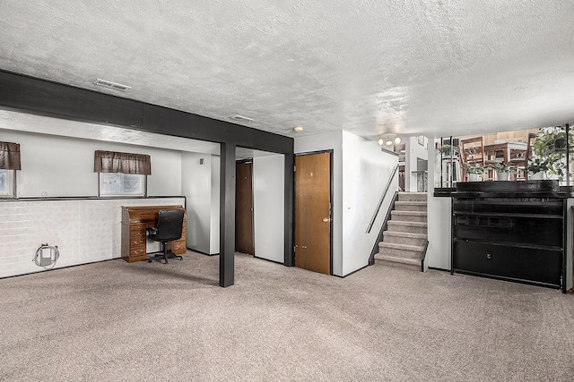 below grade area with carpet floors, stairs, a textured ceiling, and visible vents