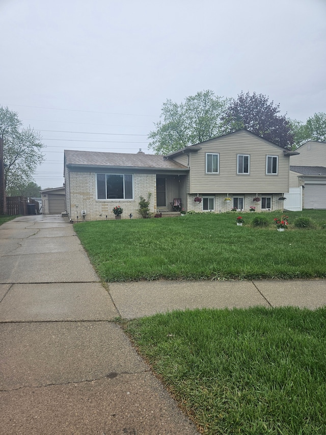 tri-level home with concrete driveway, brick siding, and a front yard