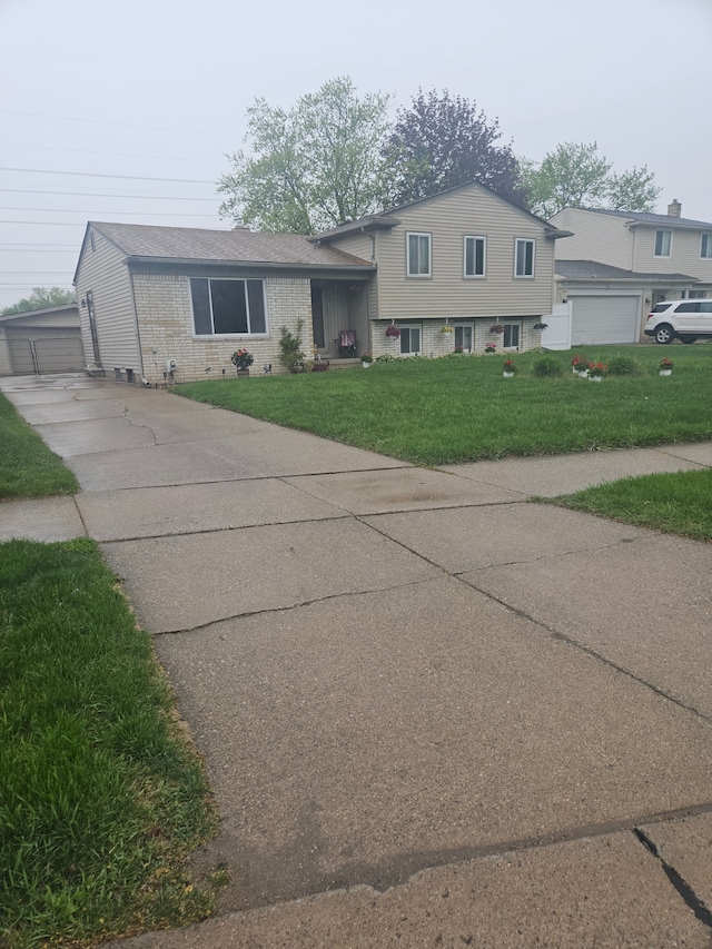 tri-level home featuring an outbuilding, concrete driveway, a front lawn, and brick siding
