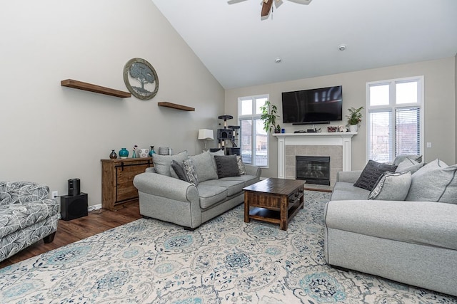 living room with a tile fireplace, high vaulted ceiling, ceiling fan, and hardwood / wood-style floors