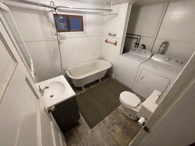 bathroom featuring a tub to relax in, vanity, washer and dryer, and toilet