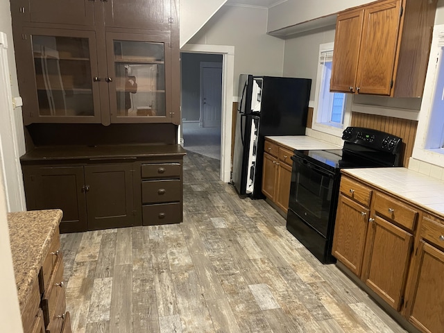 kitchen featuring ornamental molding, light hardwood / wood-style floors, and black appliances