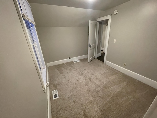 unfurnished bedroom featuring light carpet and vaulted ceiling