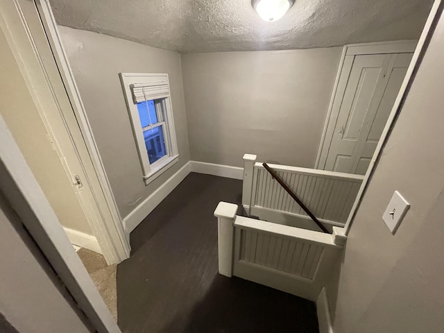 stairway featuring wood-type flooring and a textured ceiling